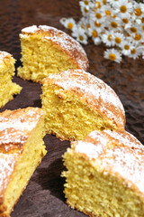 Pieces of cake made from homemade dough are on table with bouquet of daisies. Beautiful pieces of cake. Vertical photo.