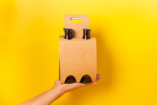 Hand holding a four pack beer presentation with yellow background