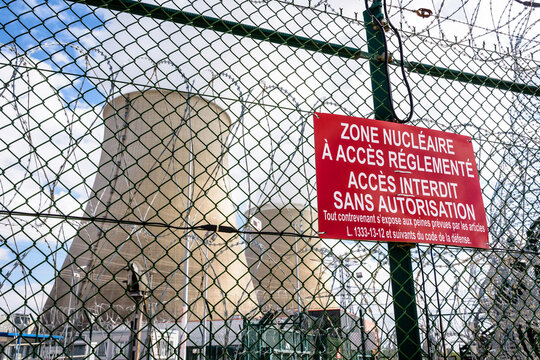 Close-up view of a warning sign on the security fence with barbed wire of a nuclear power plant in France. The sign reads "Nuclear area with restricted access. Forbidden access without authorization".
