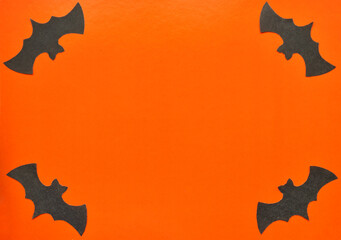 Black paper bats lie on an orange background.