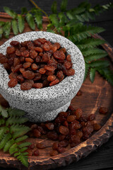 Close up of yellow raisins in a stone bowl, close up, dark background