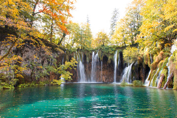 Autumn landscape with waterfalls and amazing lake. Yellow and orange trees near blue water. The Plitvice Lakes National Park in Croatia.