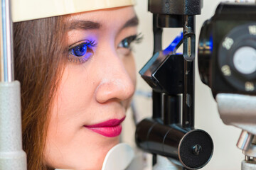 Beautiful businesswoman looking at eye test machine in ophthalmologist. health concept.