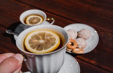 Tea party with delicious food and sweets. Ceramic white Cup and tea set. Hold a Cup of tea with lemon in your hand.