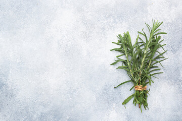 Bunch of fresh rosemary sprigs on a grey concrete background with copy space.
