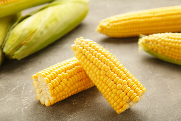 Fresh corn on cobs on rustic wooden table, closeup. Ripe corn. Half of broken open sweet corn.
