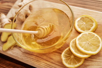 Fototapeta na wymiar Close up of fresh ginger, lemon, honey in a bowl with dipper on the wooden board, Preparation of cold and flu remedy cure drink