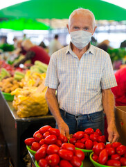 retired european man wearing medical mask protecting against virus buying tomatoes in market