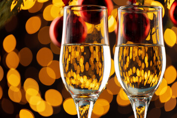 Two glasses of champagne and Christmas baubles on bokeh lights background