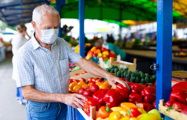 retired european man wearing medical mask protecting against virus buying tomatoes in market