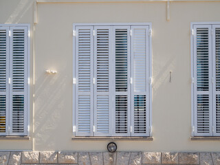 Mediterranean wooden window with shutters in the yellow house wall