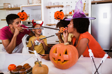 Happy family mother father and children prepare for Halloween. They are carving pumpkin.