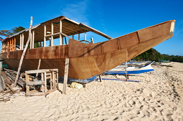 A wooden filipino banca style outrigger boat is being build along a sandy beach on Boracay Island, Philippines, Asia
