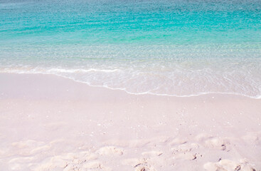 Pink sandy beach and washing by turquoise sea wave