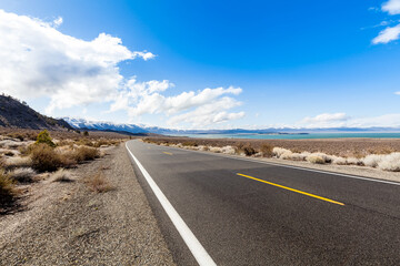 Route 120 is a seasonal road which is closed for part of the year, just opened there is still snow on the mountains, Mono Lake on the right of the road that winds through the Eastern Sierras.