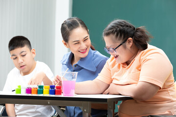 asian disabled kids or autism child learning and painting at paper with teacher helping in classroom
