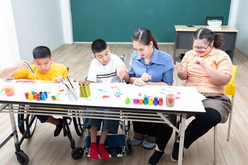 asian group of disabled kids or autism child learning and painting at paper with teacher helping in classroom