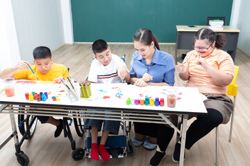 asian group of disabled kids or autism child learning and painting at paper with teacher helping in...