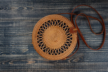 Modern stylish round straw bag on the wooden background