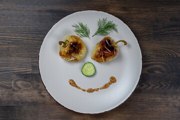 Baked yellow pepper, cucumber, green dill and french old-fashioned dijon mustard on a plate in the shape of a happy face, top view