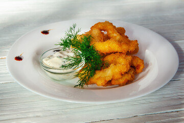 Deep-fried breaded onion rings on a plate with herbs
