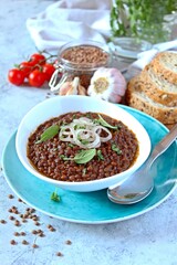 Lentils with stewed onion and tomato in a white bowl. Diet food. Top view with copy space.