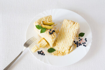Two pieces of Napoleon cake on white plate with a fork on white background. Selective focus, top view