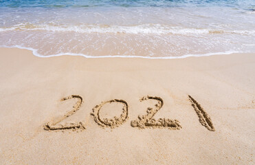 2021 year message handwritten in sand on beautiful beach background. New Years concept.