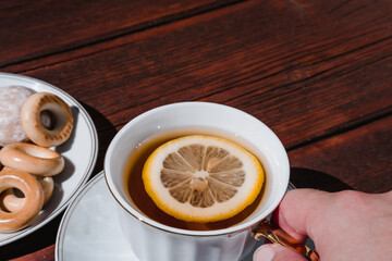 Tea party with delicious food and sweets. Ceramic white Cup and tea set. Hold a Cup of tea with lemon in your hand.