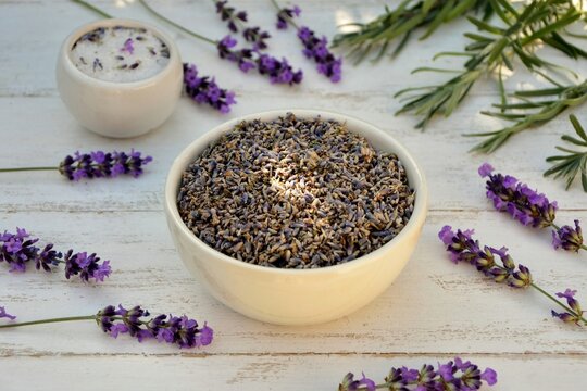 Dry lavender flowers in white bowl and aromatic salt on white wooden background with fresh lavender twigs close-up