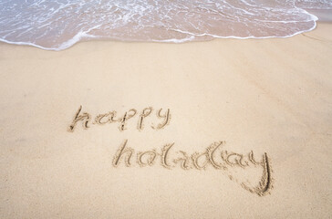 happy holiday written in the sand