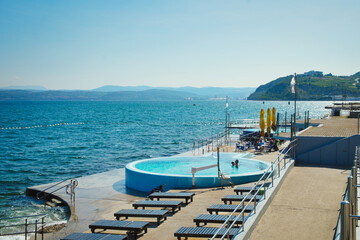 Fototapeta premium Weekend vibes and summertime refreshment in the open swimming pool next to the beach of Adriatic sea in Isola resort, Slovenia