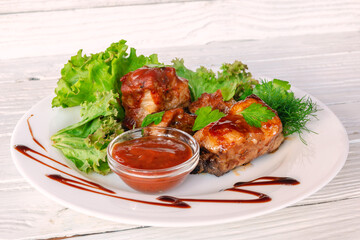 Grilled fried meat on a plate with salad and herbs, shish kebab in tomato sauce