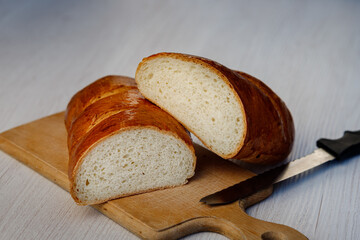 Delicious freshly baked bread and a knife on the kitchen board