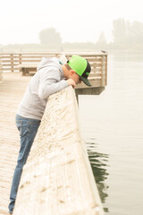 boy looking into the water off a pier 