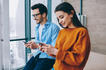 Caucasian millennials using modern cellphones for sharing media files via bluetooth connection,...
