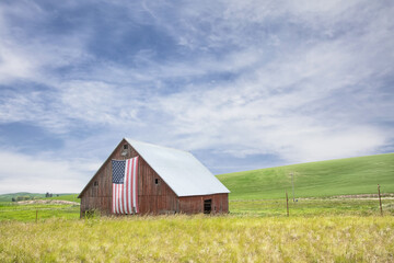 Original photograph of an old red barn with an American flag hung from the front 