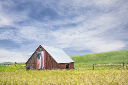 Original photograph of an old red barn with an American flag hung from the front 