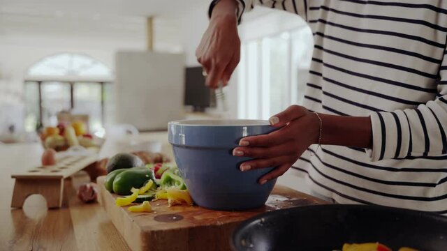 Close-up of a woman preparing the food in kitchen, beating eggs and pouring it into a pan with vegetables to make a healthy breakfast