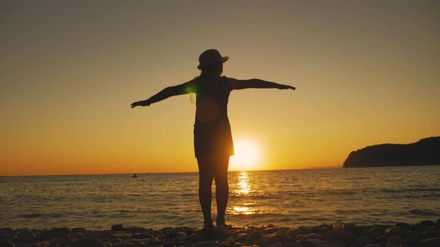 Silhouette of happy child playing at the beach at sunset, dreaming about flying. Summer vacation and travel concept.
