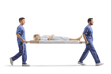 Full length profile shot of healthcare workers carrying a female patient on a stretcher
