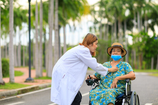 Asian female doctor taking care of senior patient in the garden.