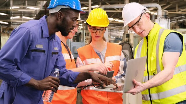 Industrial engineers talking with factory worker while using laptop in manufacturing plant.Teamwork brainstorming for maintenance machine in manufacturing plant.