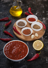 Hot seasoning harissa, ground spices, hot chili peppers, vegetable oil and lemon on a black background.