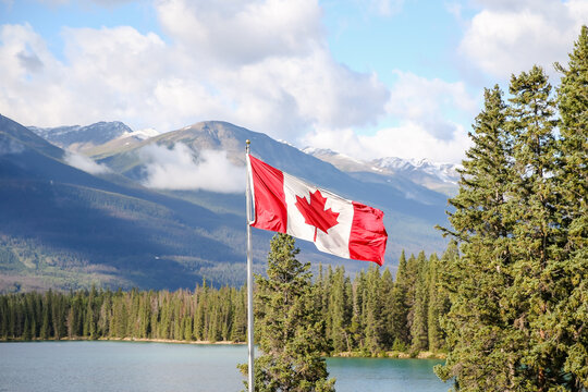 The national flag of Canada against a blue sky in the Canadian Rockies