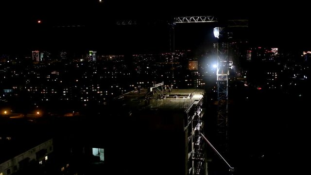 Construction workers pouring wet concrete using concrete spider hose or pump work at high-rise site in night