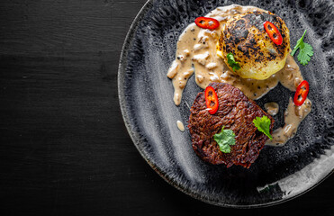 Grilled beef steak filet mignon with potato and sauce in plate on wooden table