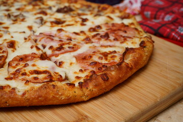 Pizza de jamón y queso en tabla de madera