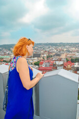 Fototapeta na wymiar Redhead woman looking at city Lviv from town hall in Ukraine