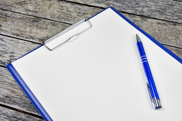 Empty clipboard with pen on an old wooden table